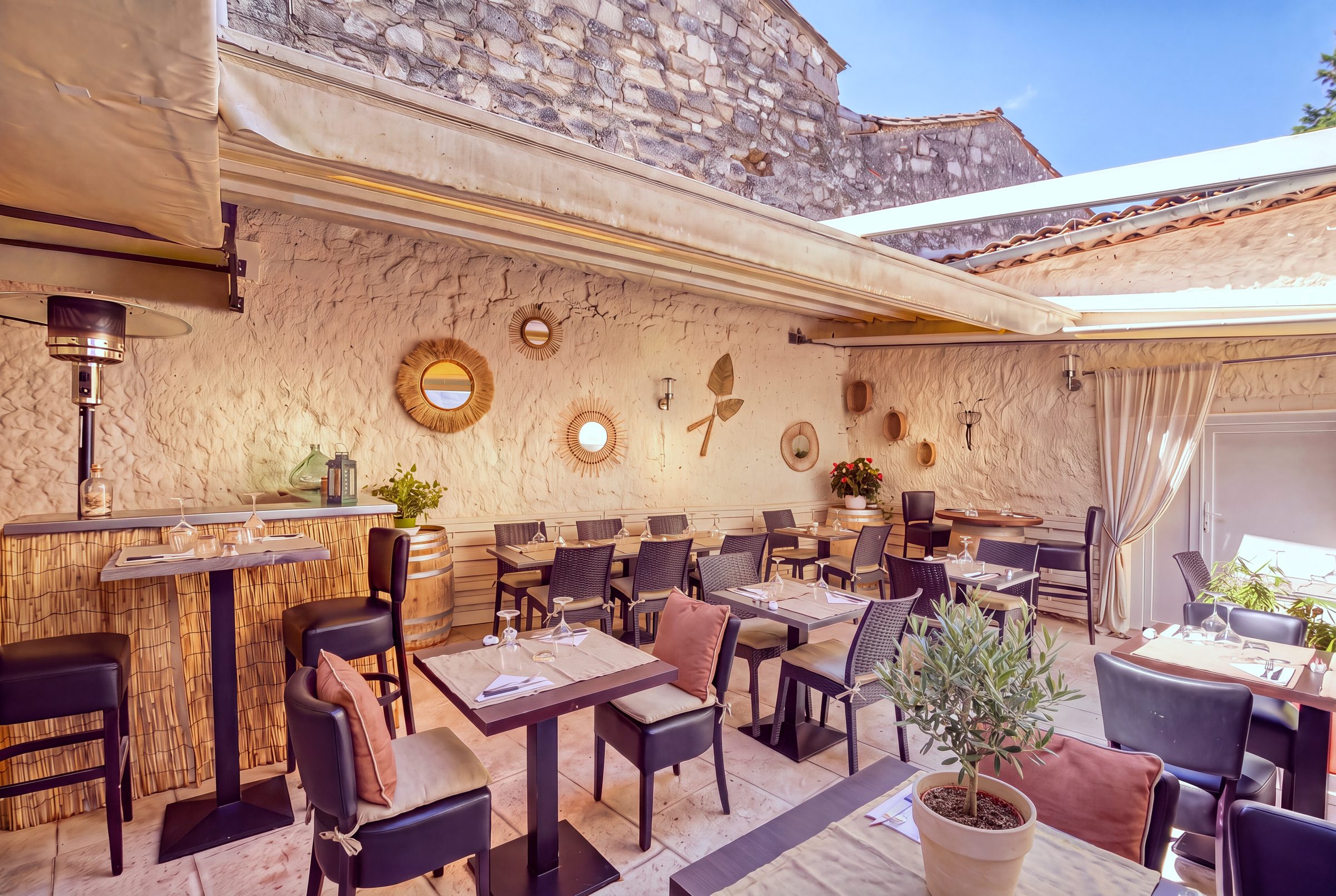 Le patio du Patio d'Eve sous le soleil, murs chaulés, miroirs en rotin et olivier