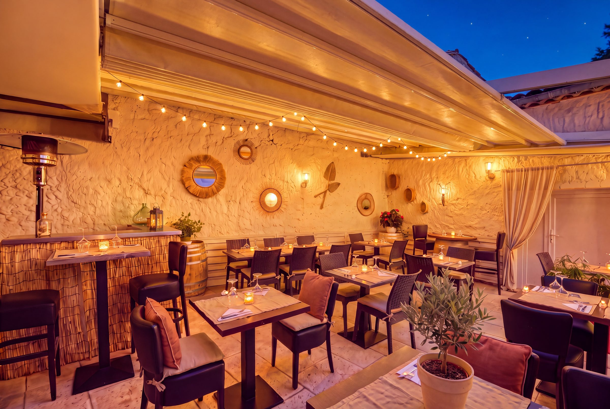 Le patio le soir, toit rétractable à demi fermé et guirlandes lumineuses